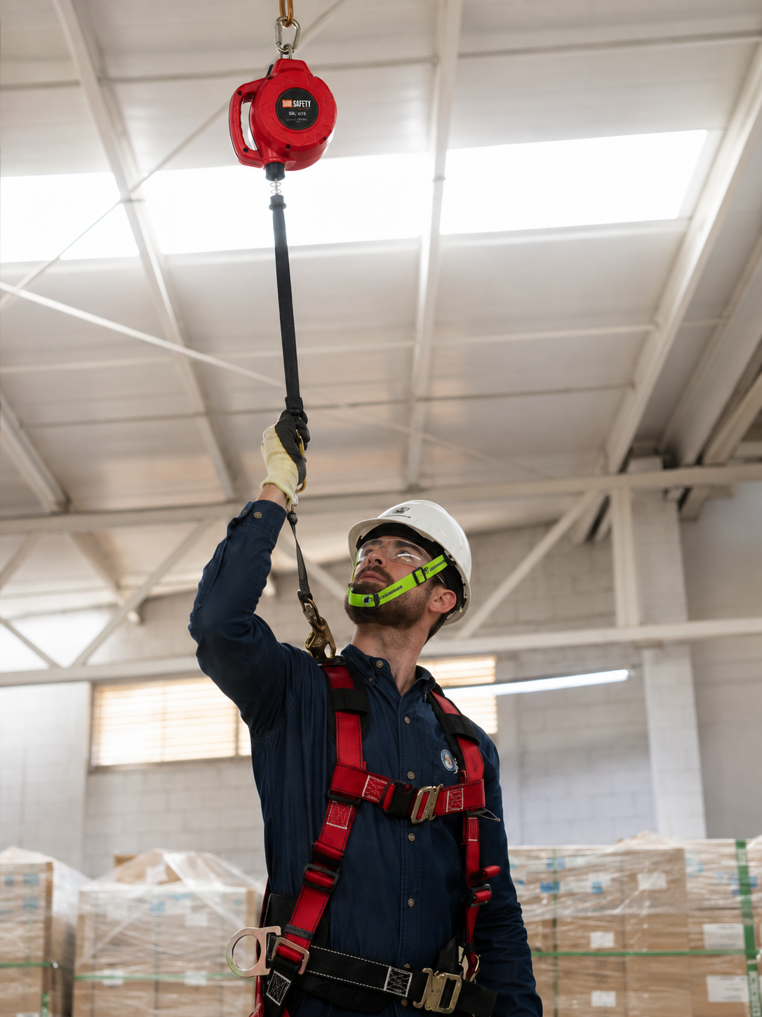 Operario con arnés conectando su línea a un dispositivo retráctil SUR Safety en planta industrial
